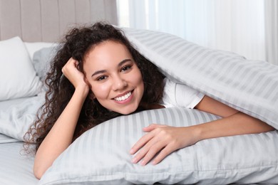 Photo of Happy beautiful African American woman lying in bed at home