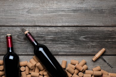Photo of Wine corks, bottles and corkscrew on wooden table, flat lay. Space for text