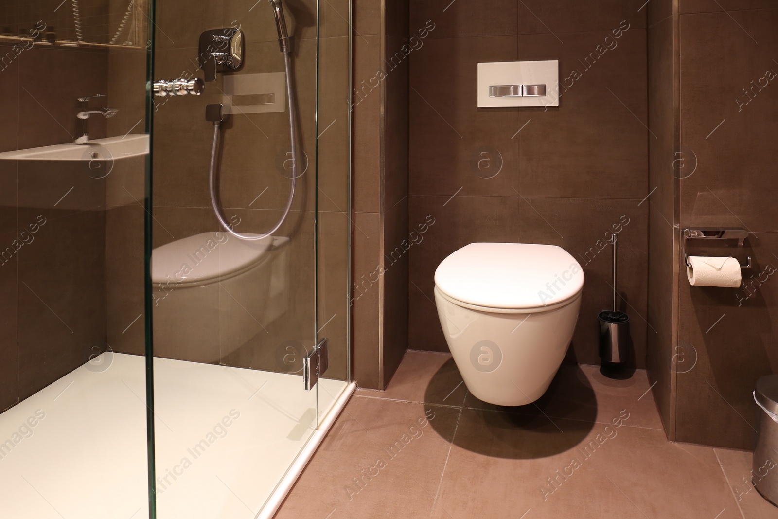 Photo of Stylish bathroom with toilet bowl and shower stall in luxury hotel. Interior design