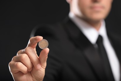Photo of Businessman holding coin on black background, closeup. Space for text