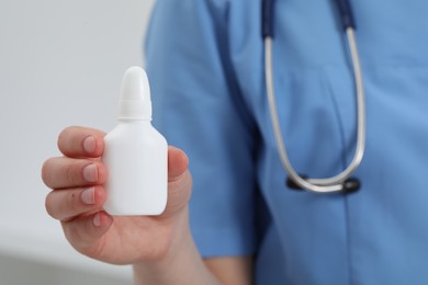 Doctor holding nasal spray on white background, closeup