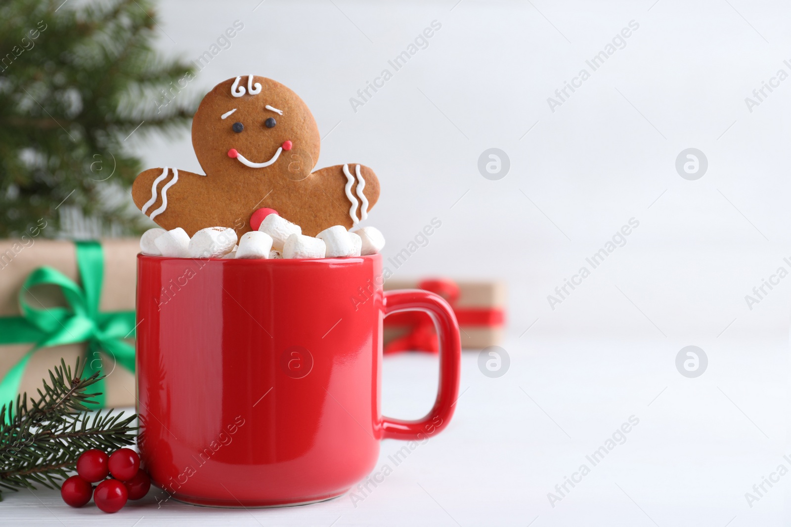 Photo of Gingerbread man in red cup with marshmallows on white table, space for text