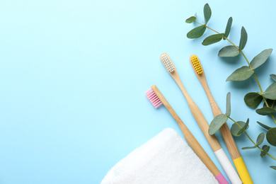 Flat lay composition with toothbrushes made of bamboo on light blue background. Space for text