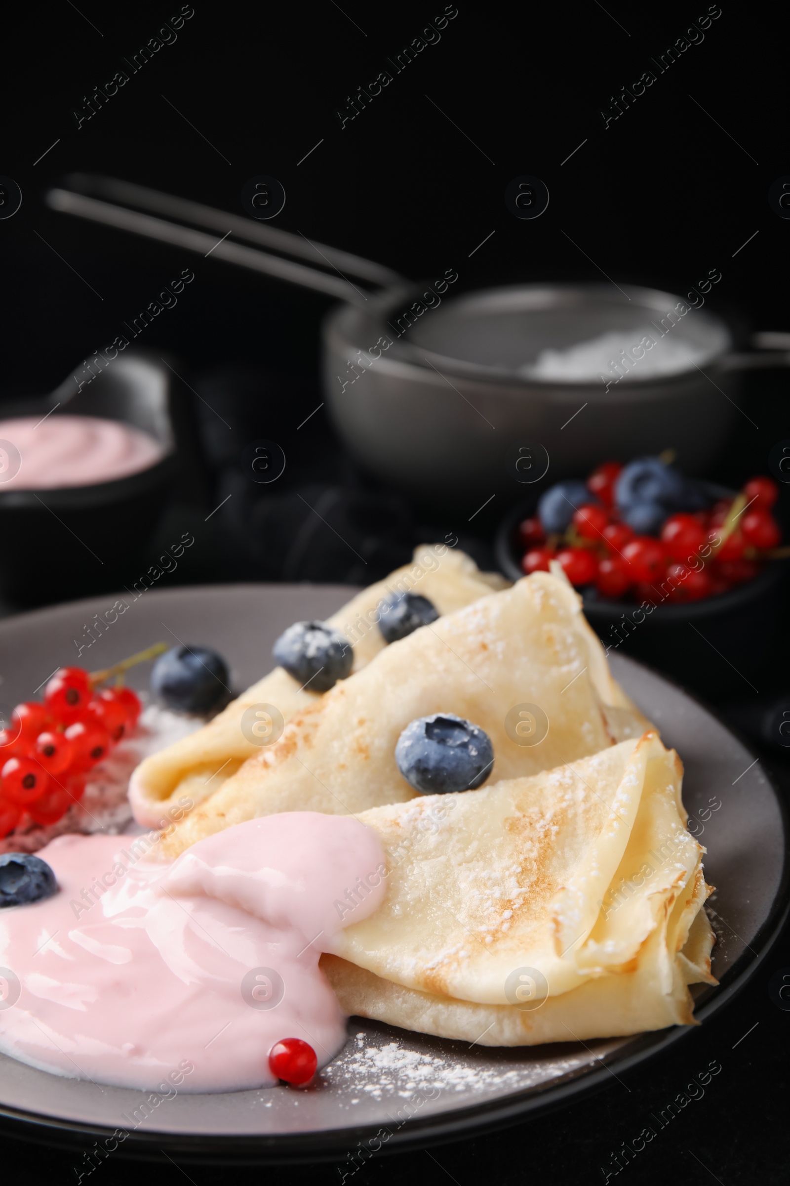 Photo of Delicious crepes with natural yogurt, blueberries and red currants on table, closeup