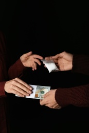 Drug dealer selling cocaine to addict on black background, closeup