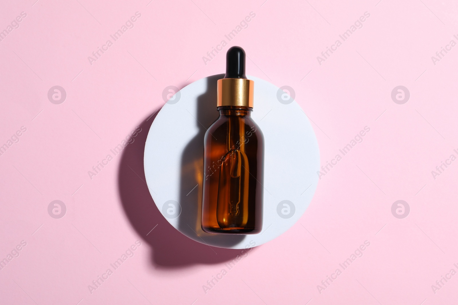 Photo of Bottle of cosmetic oil on pink background, top view