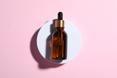 Bottle of cosmetic oil on pink background, top view