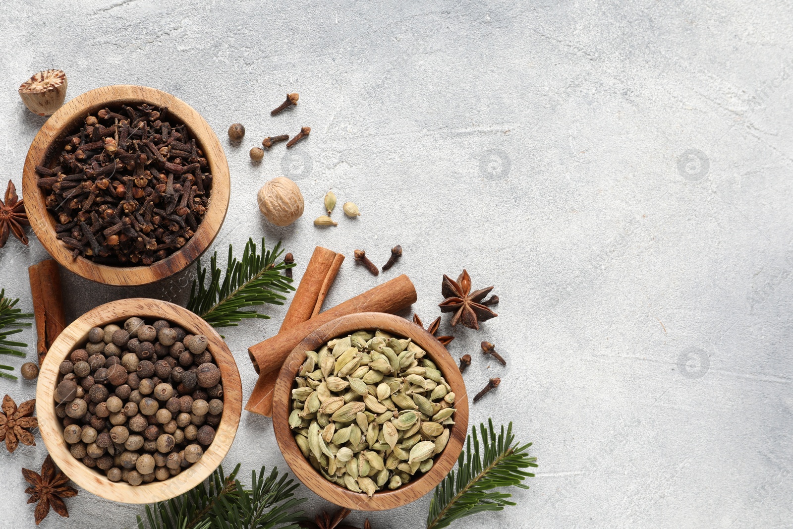 Photo of Different aromatic spices and fir branches on light textured table, flat lay. Space for text