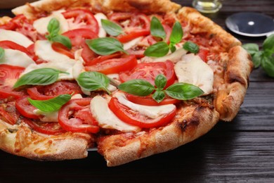 Photo of Delicious Caprese pizza on black wooden table, closeup