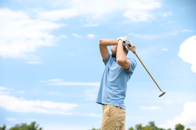 Man playing golf against blue sky. Space for text