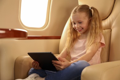 Photo of Cute little girl using tablet in airplane during flight