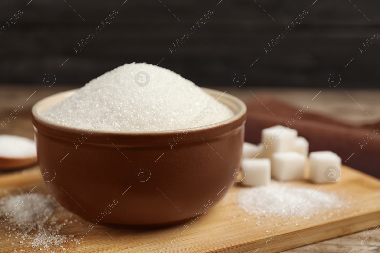 Photo of Granulated sugar in bowl on wooden table