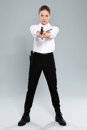 Female security guard in uniform with gun on grey background