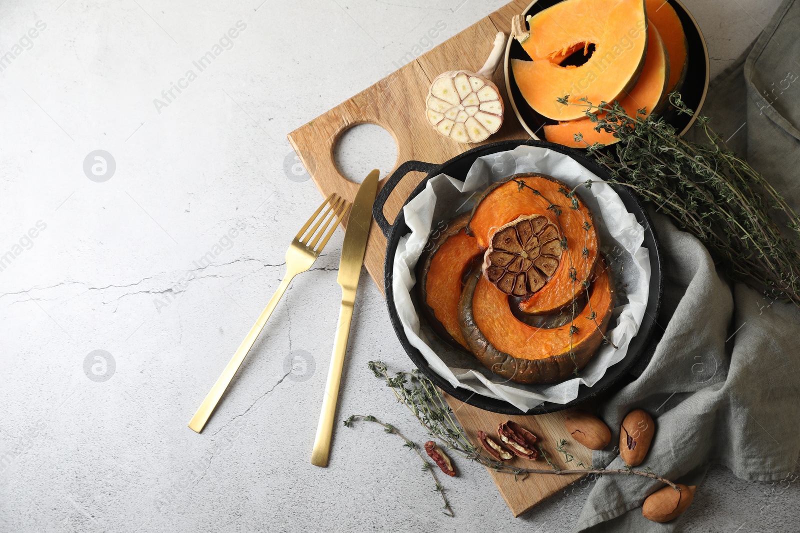 Photo of Freshly baked pumpkin slices with garlic and thyme on light table, flat lay. Space for text
