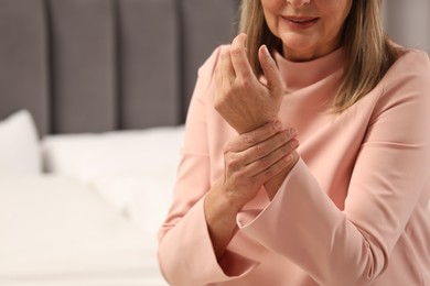 Mature woman suffering from pain in hand indoors. Rheumatism symptom