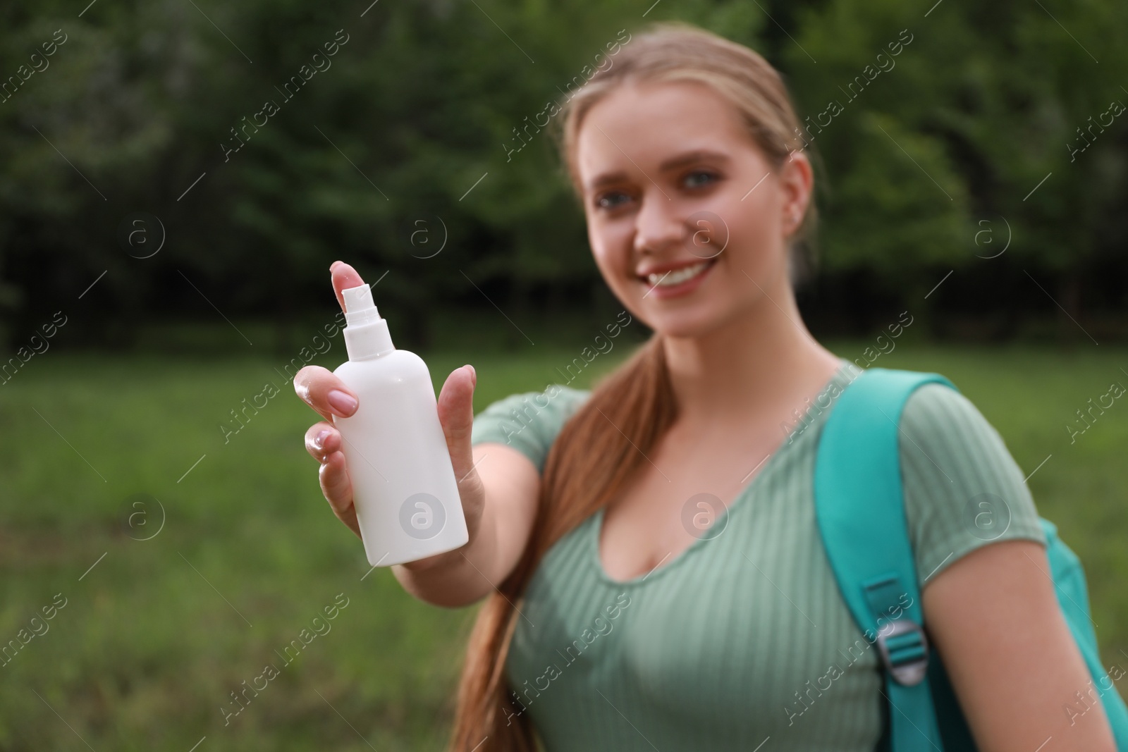 Photo of Woman with insect repellent spray in park, focus on bottle. Tick bites prevention