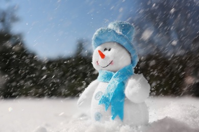 Cute small decorative snowman outdoors on winter day, space for text