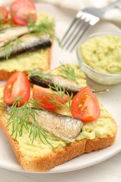 Photo of Delicious sandwiches with sprats, tomatoes, dill and avocado puree served on white table, closeup