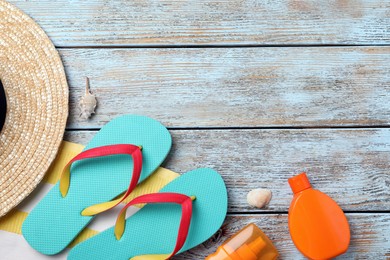 Stylish flip flops and beach objects on light wooden background, flat lay. Space for text