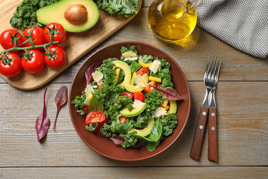 Photo of Tasty fresh kale salad on wooden table, flat lay