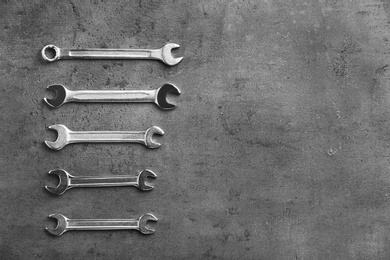 Photo of New wrenches on grey background, top view with space for text. Plumber tools