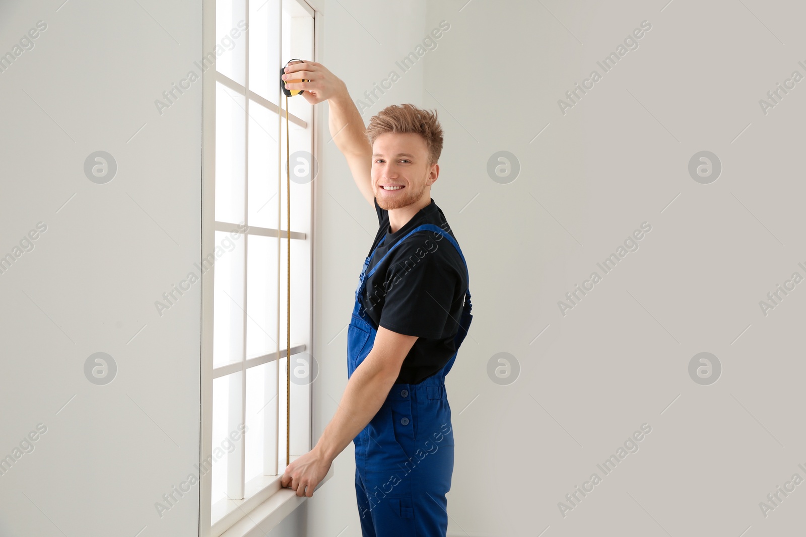 Photo of Service man measuring window for installation indoors. Space for text