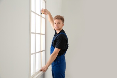 Service man measuring window for installation indoors. Space for text