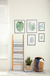 Beautiful paintings of tropical leaves on white wall in room interior