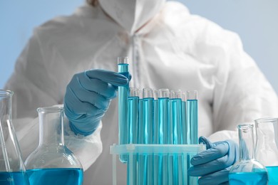 Photo of Scientist taking test tube with light blue liquid on grey background, closeup