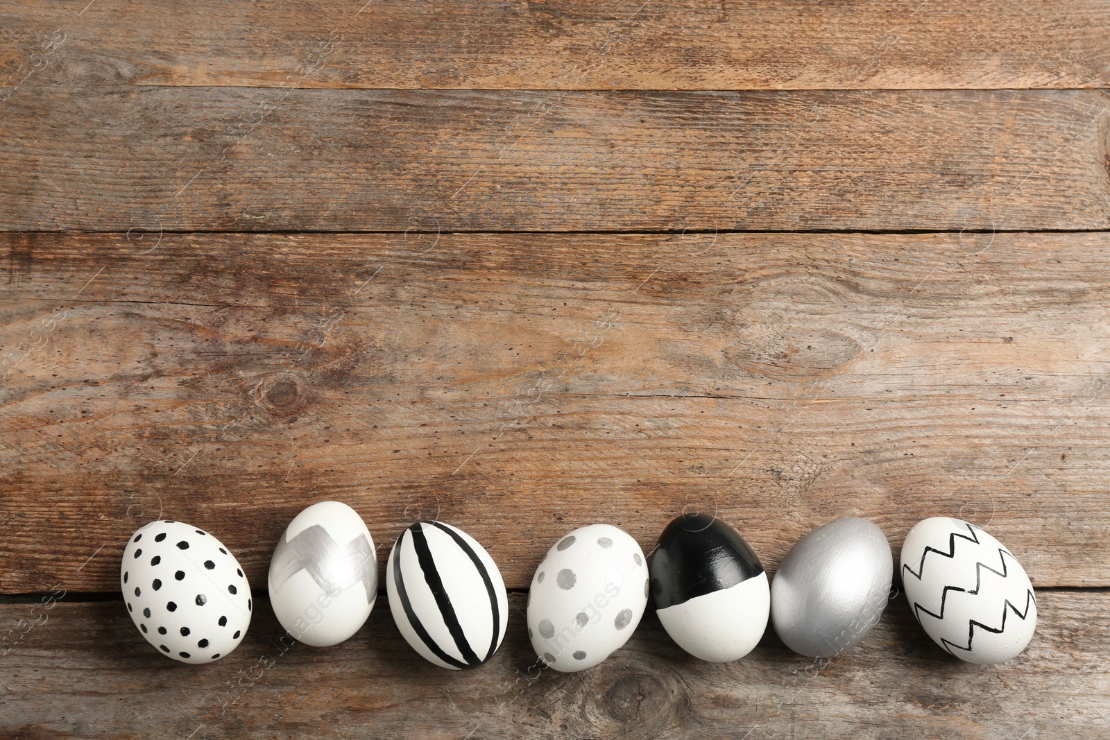 Photo of Painted Easter eggs on wooden background, flat lay with space for text