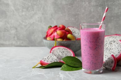 Photo of Glass of tasty pitahaya smoothie and fresh fruits on light grey table, space for text