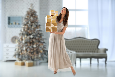 Image of Beautiful woman with Christmas gifts at home