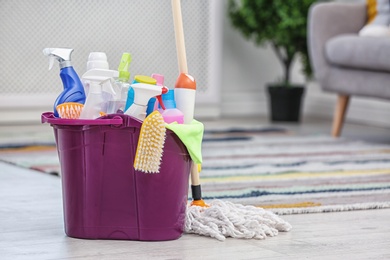 Photo of Bucket with set of cleaning supplies indoors