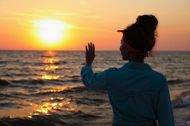 Girl near sea at sunset, back view