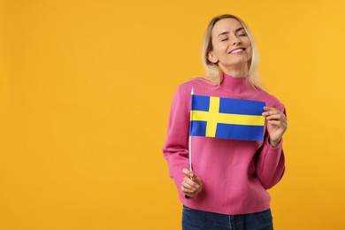 Photo of Happy woman with flag of Sweden on orange background, space for text