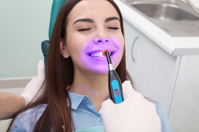 Professional dentist working with patient in modern clinic, closeup. Teeth whitening