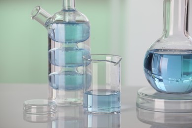 Laboratory analysis. Different glassware with liquid on white table against blurred background, closeup