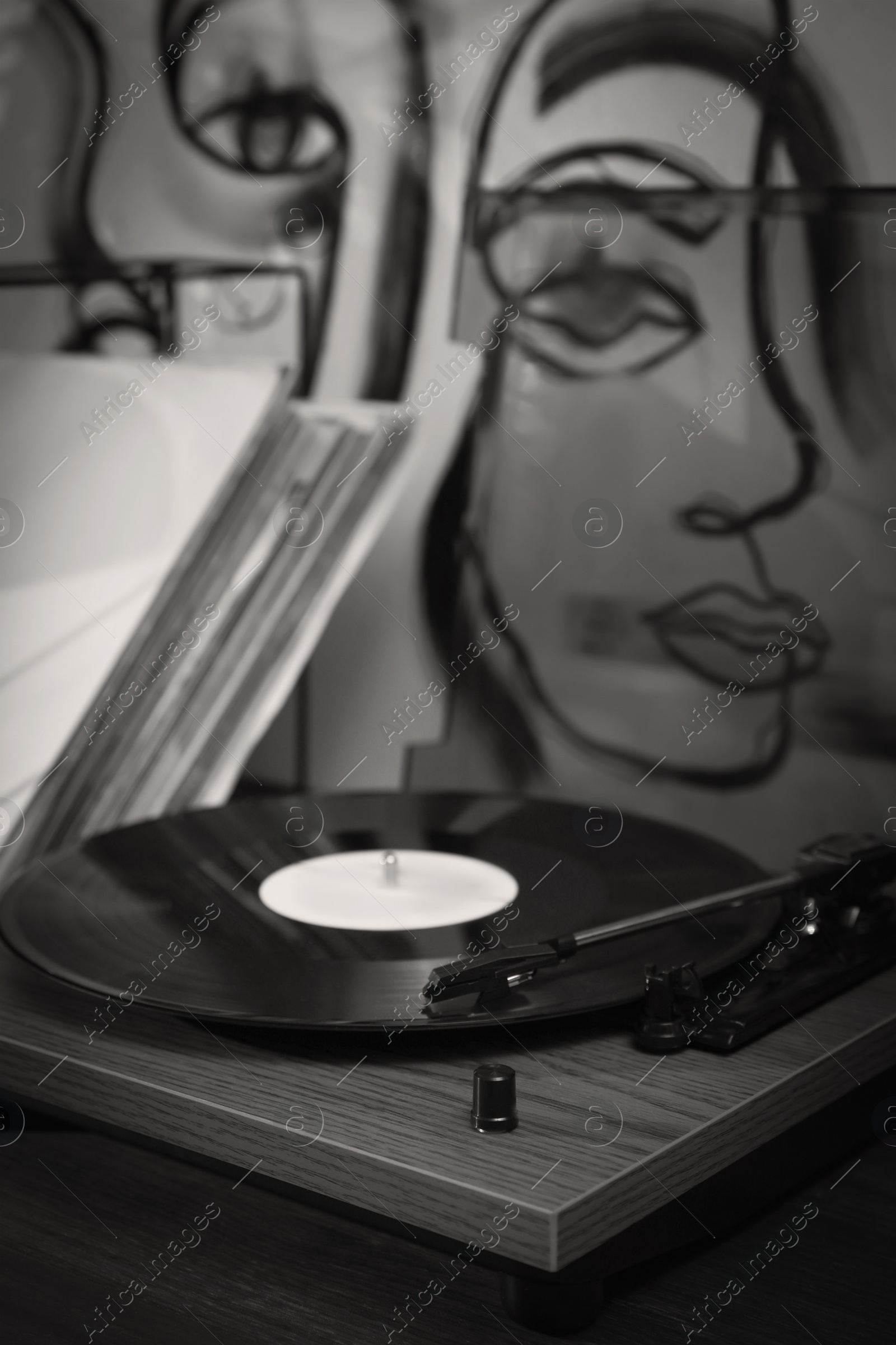 Image of Stylish turntable with vinyl disc on table in room, closeup. Black white filter