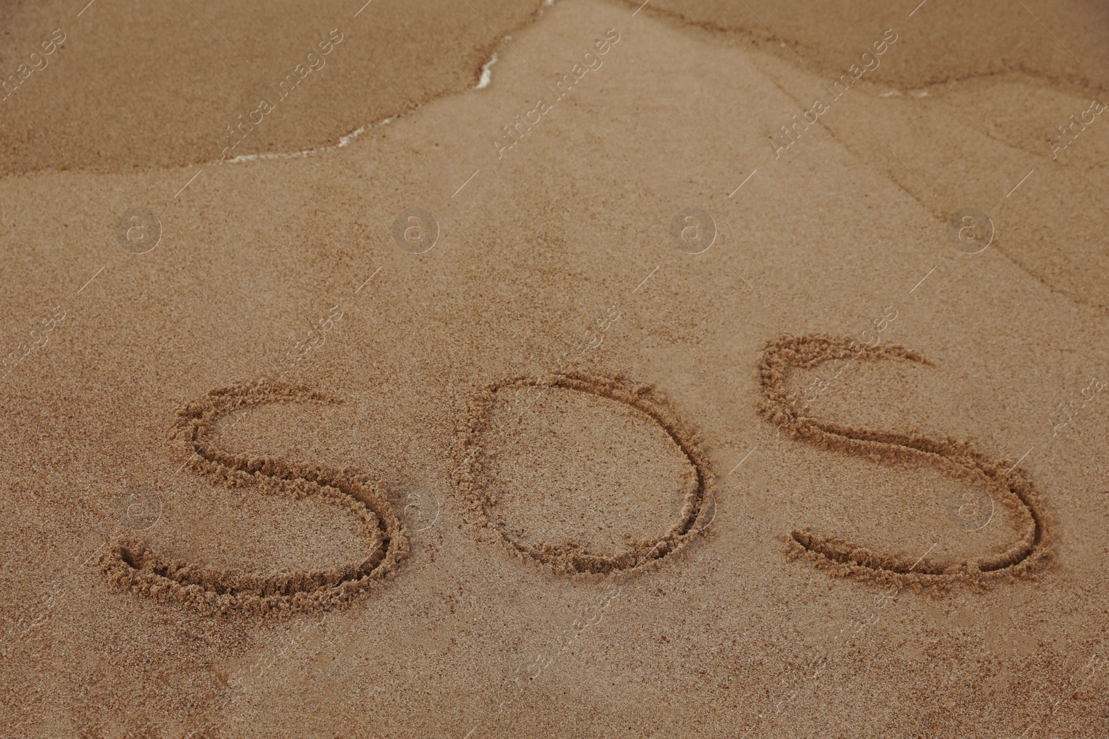 Photo of Message SOS drawn on sandy beach, space for text