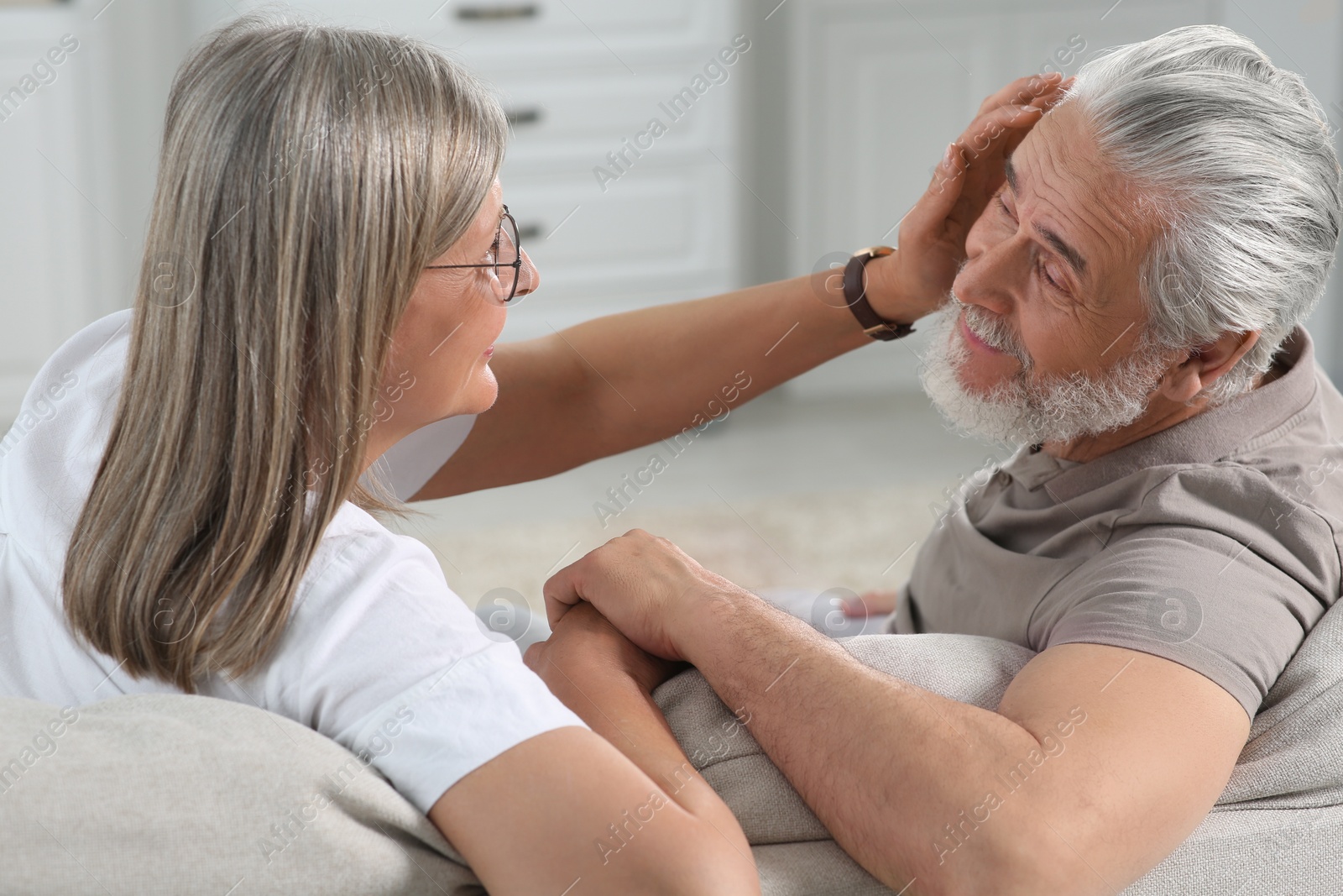 Photo of Affectionate senior couple relaxing on sofa at home