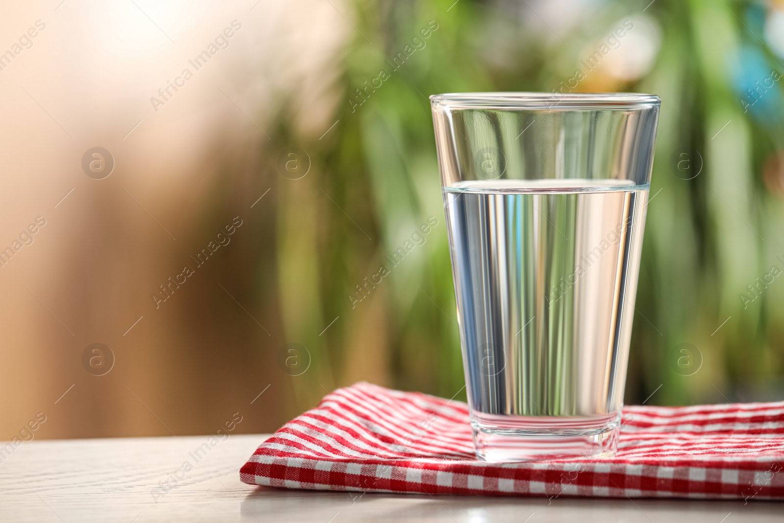 Photo of Glass of pure water on white wooden table against blurred background, space for text
