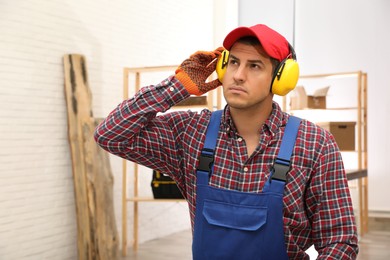 Worker wearing safety headphones indoors. Hearing protection device