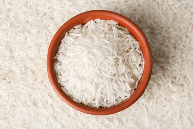 Photo of Raw basmati rice and bowl as background, top view