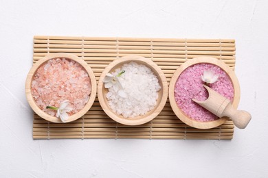 Photo of Different types of sea salt and flowers on light table, flat lay. Spa products