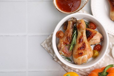 Photo of Marinade, roasted chicken drumsticks, rosemary and tomatoes on white table, flat lay. Space for text