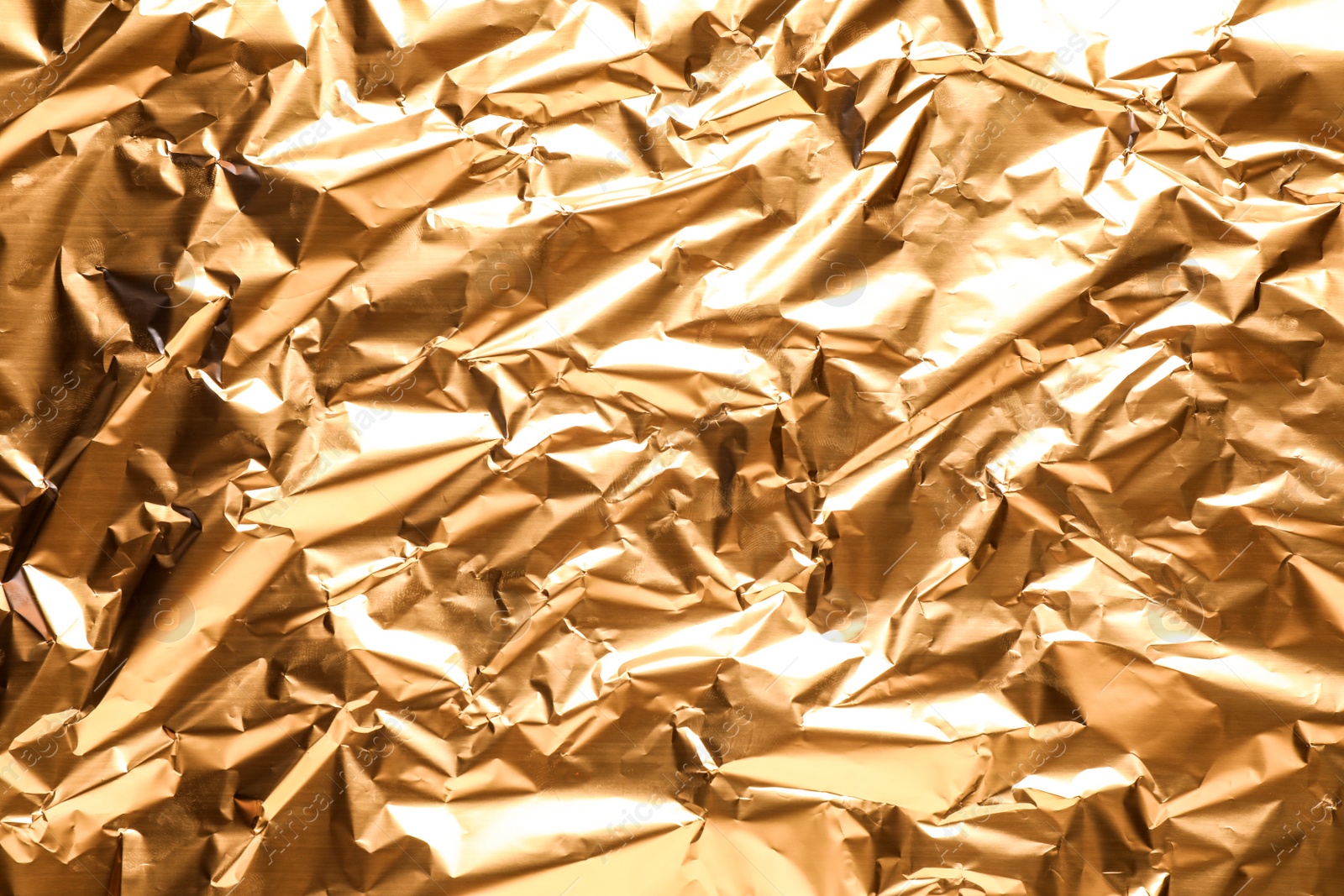 Photo of Crumpled gold foil as background, top view