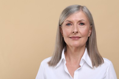 Portrait of beautiful senior woman on beige background. Space for text