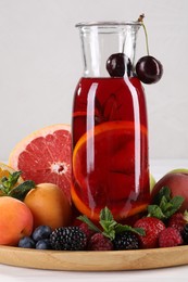 Photo of Delicious refreshing sangria, fruits and berries on white table
