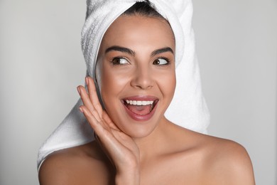 Photo of Beautiful young woman with towel on head against light background