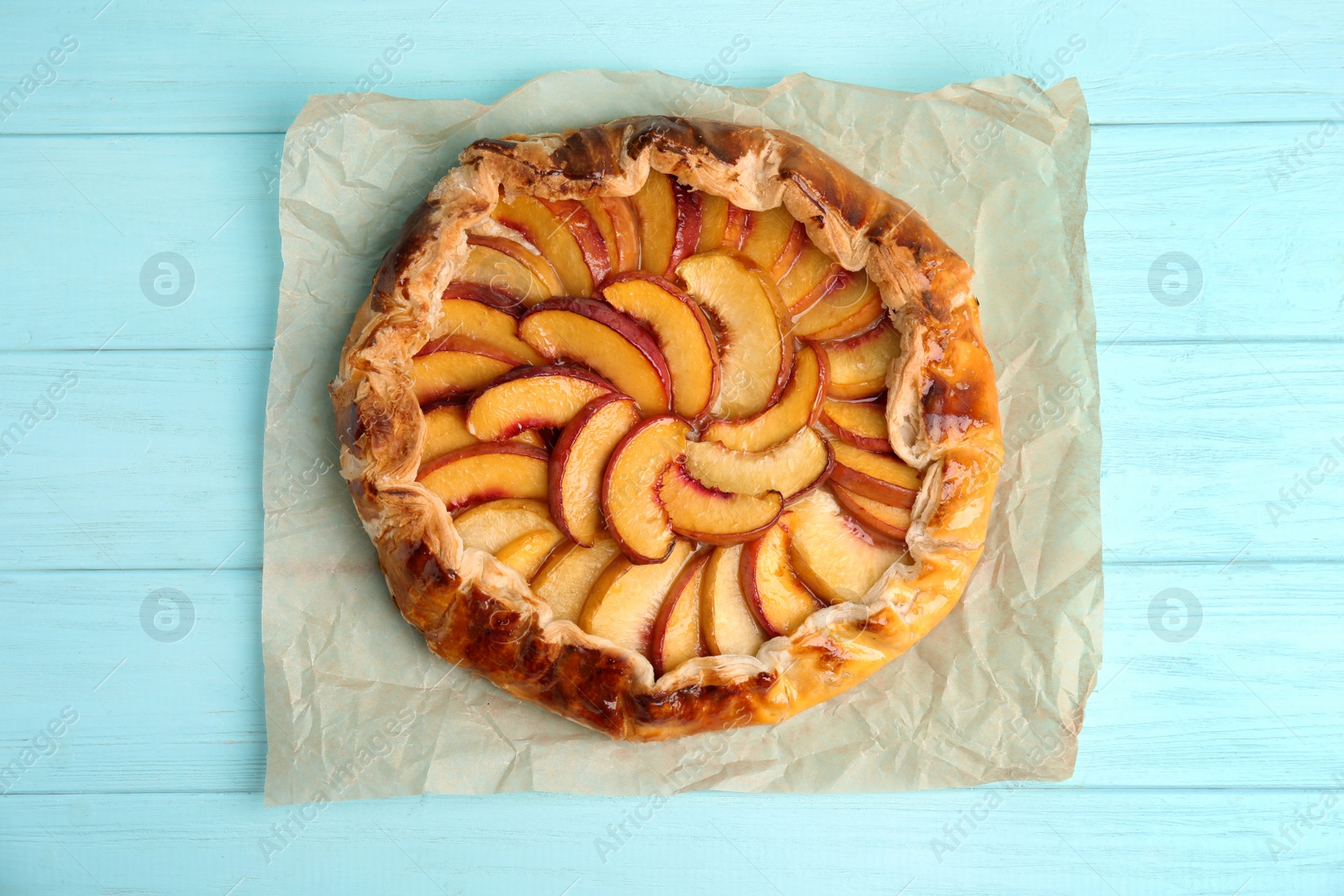 Photo of Delicious fresh peach pie on light blue wooden table, top view